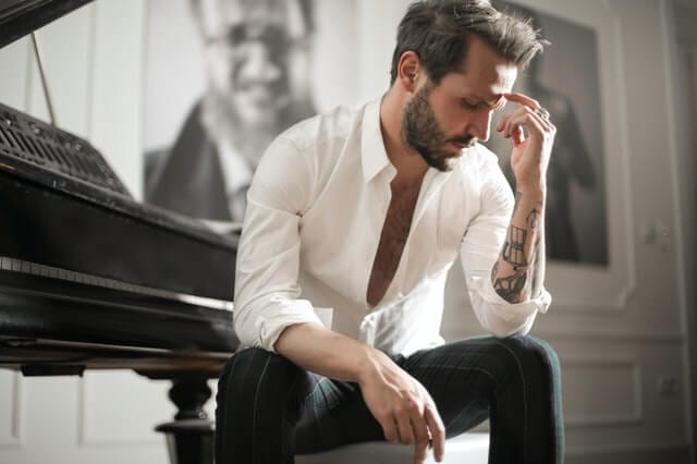 Man in white shirt sitting near piano