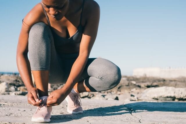 Sporty black girl ties a shoelace