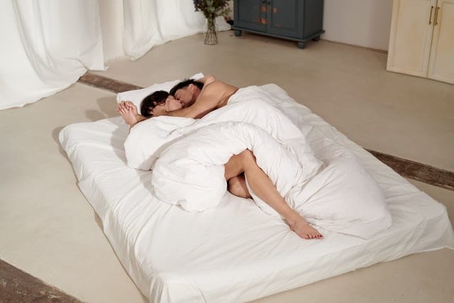 couple lying in bed covered with white blanket